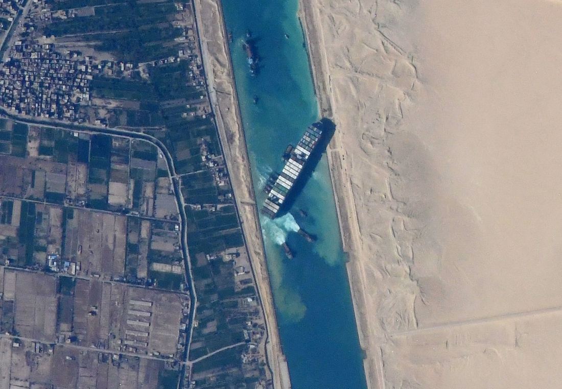 Satellitenfoto: Das Containerschiff Ever Given liegt quer im Suezkanal, links Felder, rechts Wüste